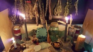 A spiritual love spell altar with red and pink candles, rose petals, and a photo of a couple.