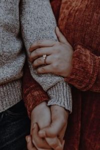 A couple holding hands with a love magic ring.