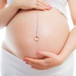 A fertility magic ring with a pregnant woman in the background.