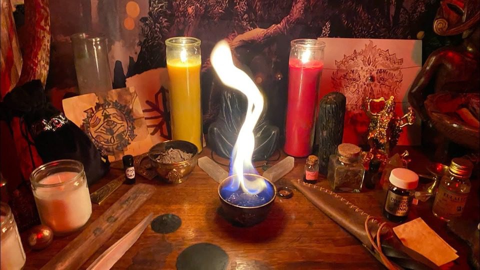 Prof. Eric Galandi smiling with sacred candles and African attire in a peaceful, magical setting-love spells in Minneapolis